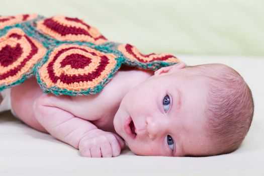 newborn baby lies, covered with a knitted blanket