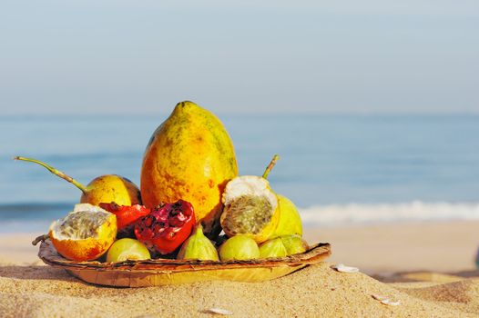 Exotic tropical fruit on the leaves plate, on the sandy beach