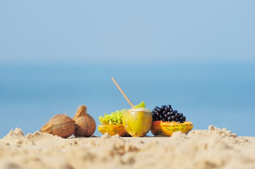 Papaya, coconut and grapes on the sandy beach