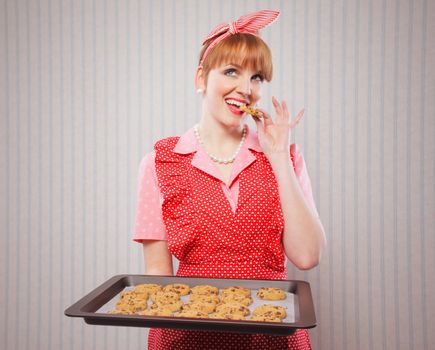 Retro housewife holding cookie tray full of chocolate cookie 
