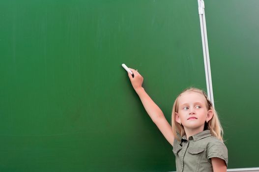 Schoolgirl writing on the blackboard, the beginning of the new academic year