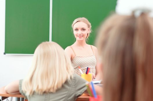 portrait of beautiful young teacher, sits at a desk in the classroom