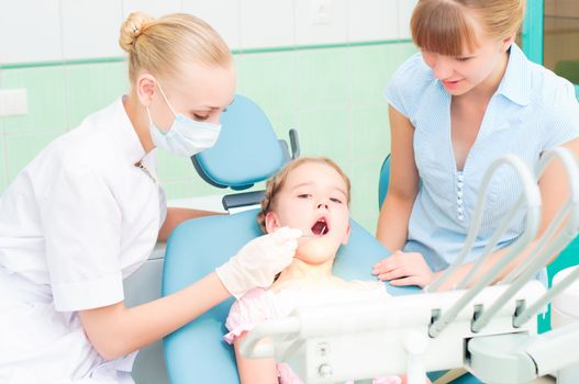 female dentists examines a child, my mother was sitting beside him and soothes baby