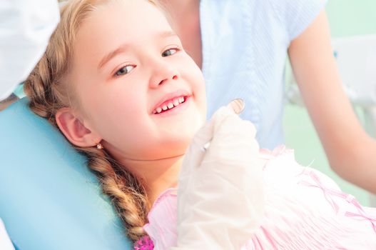 child visits a dentist, smiling and looking into the camera