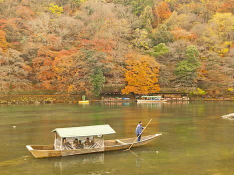 ARASHIYAMA, KYOTO, JAPAN - CIRCA DECEMBER 4, 2009: Boat with tourists on Katsura river in Arashiyama area, Kyoto, Japan on December 4, 2009.