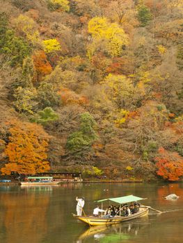 ARASHIYAMA, KYOTO, JAPAN - CIRCA DECEMBER 4, 2009: Boat with tourists on Katsura river in Arashiyama area, Kyoto, Japan on December 4, 2009.