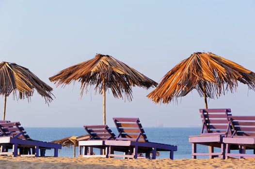 Exotic beach umbrellas and chairs on tropical coast