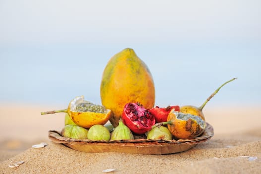 Exotic tropical fruit on the leaves plate on the sand shore
