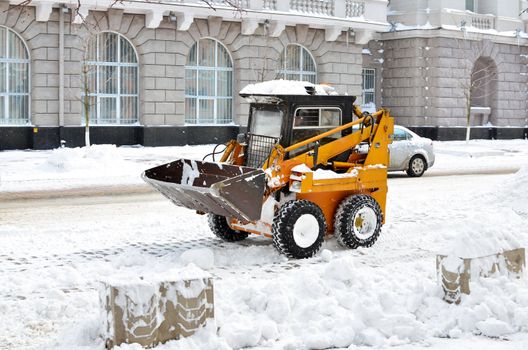 yellow tractor cleaning the snow on a street