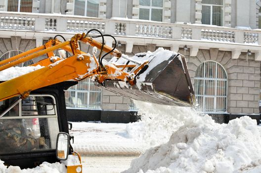 yellow tractor cleaning the snow on a street