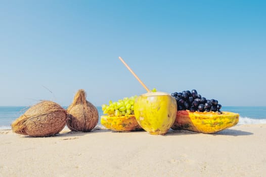 Papaya, coconut and grapes on the sandy beach