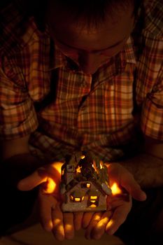 decorative house with a candle in the hands of man