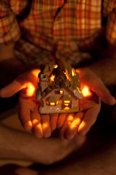 decorative house with a candle in the hands of man