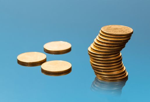 Stacks of gold eagle one troy ounce golden coins from US Treasury mint contrasted on blue reflecting background with fade