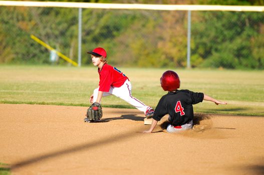 Little league baseball player getting an out at second base.