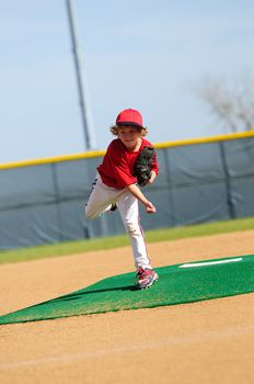 Young baseball pitcher on the pitching mound after the pitch.