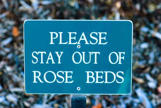 Sign that says Please stay out of rose beds.