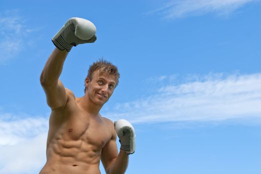 Young guy boxing. Outdoor training under blue sky.