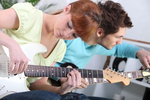 Young couple tuning and playing guitar