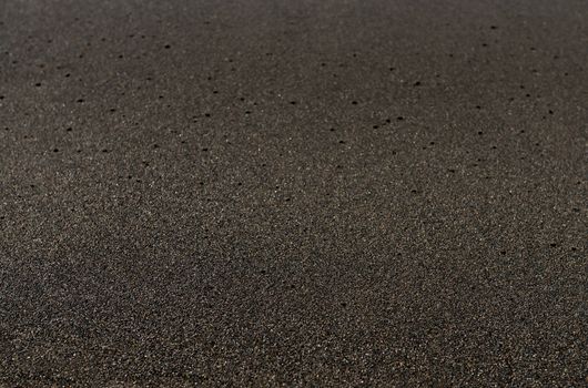 Black sand volcanic beach background in Bali, Indonesia. Shallow depth of field.