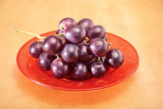 Fresh grapes on the plate on a wooden table.