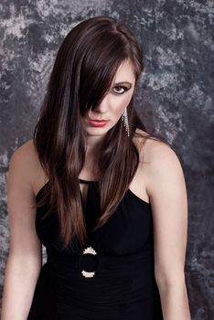 Portrait attractive brunette in black dress. Fashion studio shot