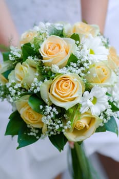 bride holding beauty wedding bouquet of yellow roses and white camomile