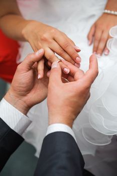 wedding engagement ceremony. Bridegroom put the ring on one's finger of bride 