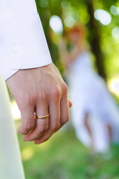 golden ring on one's finger of bridegroom. looking at bride on a blur background