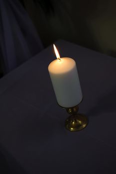 one light thick candle on a dark background with tall flame