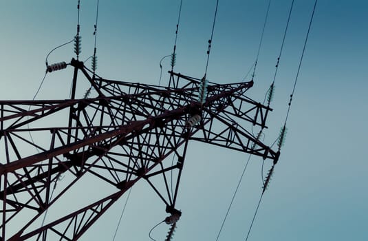 silhouette of high metal electricity tower with wire. Sunset time. Unusual perspective