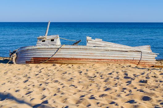 old wooden fishing boat  lying on a seashore. Clear and sunny day. fair weather and blue sky