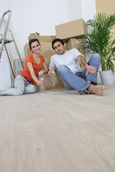 Couple sitting on the floor with moving cardboards