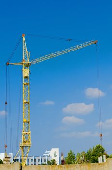 high yellow hoisting crane on a blue sky background