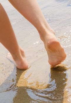 young woman take a walk on wet seashore. Body part.