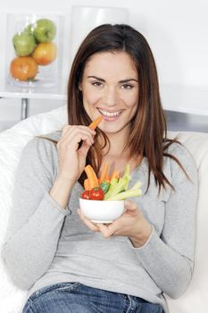 smiling woman on sofa with vegetable salad