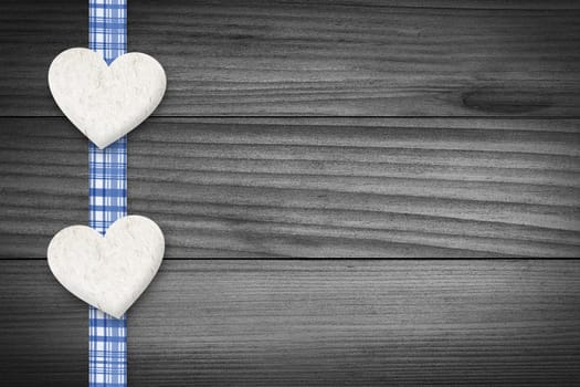 Two hearts and a blue checkered texture stripe laying on wood.
