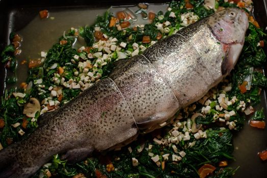 filled rainbow trout (salmon trout) on spinach with tomatoes and mushrooms ready for the oven