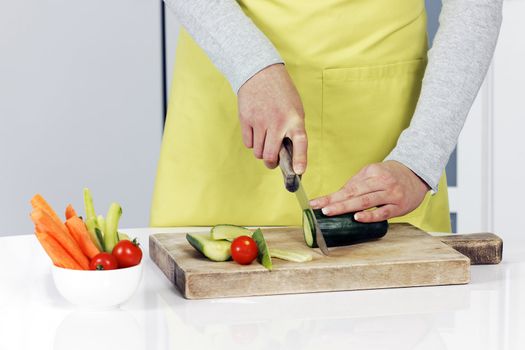 Cutting cucumber and vegetables on background 