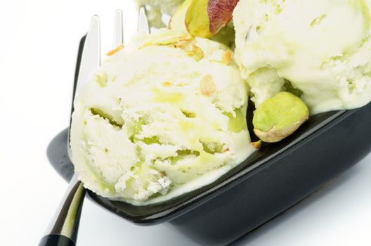 Two Balls of Pistachio Ice Cream in Black Plate with Dessert Fork closeup
