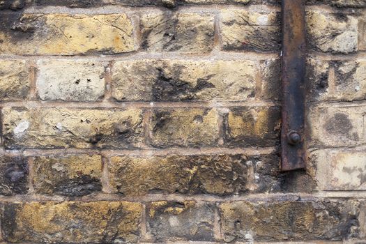 Brick background with chips and discoloration and a metal bar