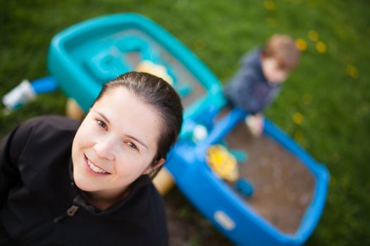 Happy mother in front of her child playing