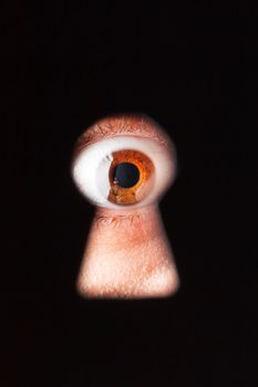 Eye looking through a keyhole