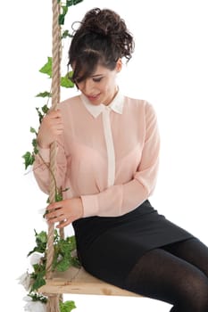 A woman in a pink blouse sitting on a swing isolated white background