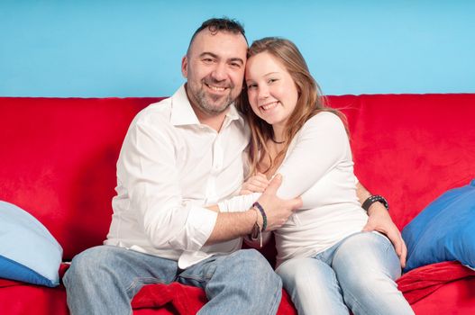 happy father and teenage daughter on the couch in the living room