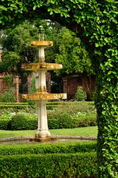 An arch frames a view of a fountain in this formal garden