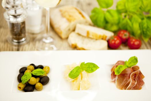 deliscious antipasti plate with parma parmesan olives on wooden background