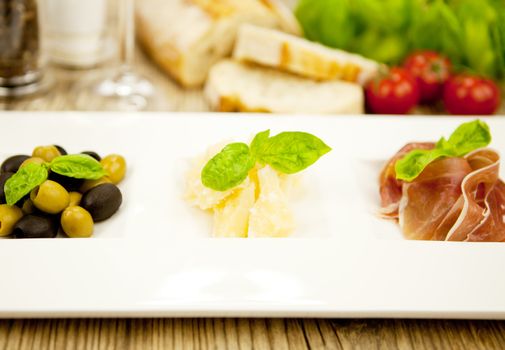 deliscious antipasti plate with parma parmesan olives on wooden background