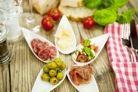 deliscious antipasti plate with parma parmesan olives on wooden background