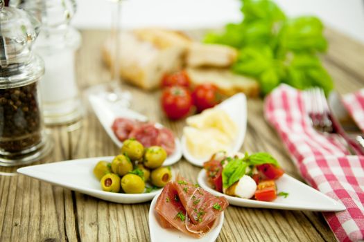 deliscious antipasti plate with parma parmesan olives on wooden background